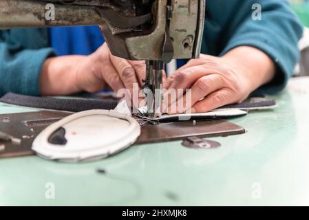 Leather patterns are sewn together by skilled hands to produce the product in greater quantity. Stock Photo