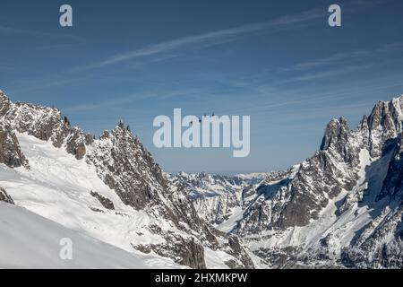 Looking down the Vallee Blanche off-piste itinerary with the panoramic cable cars connecting France and Italy suspended above the glaciers merging in Stock Photo