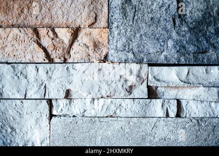 A dimly lit textured wall of multicolored stone bricks Stock Photo