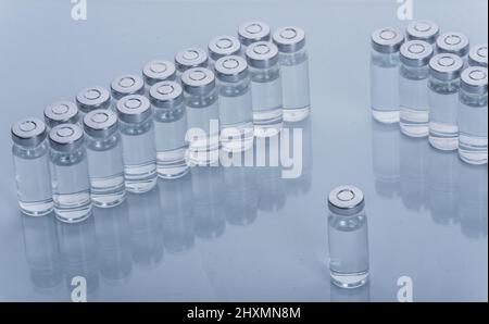 Glass medical ampoule vial for injection. Medicine is dry white drug penicillin powder or liquid with of aqueous solution in ampulla. Close up. Bottles ampule with aluminum cap on backgrounds gray. Stock Photo