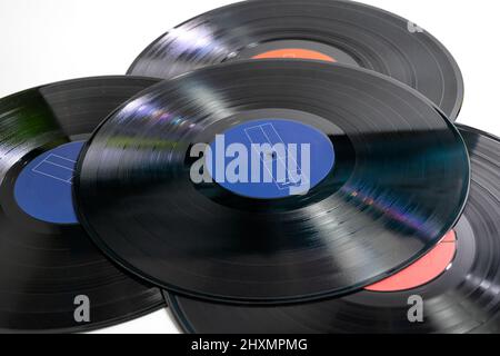 Stack of four traditional glossy black vinyl records without scratches on a white table Stock Photo