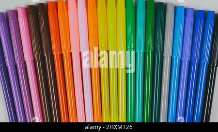 Many colored pencils are arranged around the edges of the image as a frame. In the center is an empty background with space for text. Mock up with copy space. Stock Photo