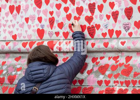 People give their dedications on newly painted hearts on the COVID wall.   29th March 2022 marks the one year anniversary of the first heart being dra