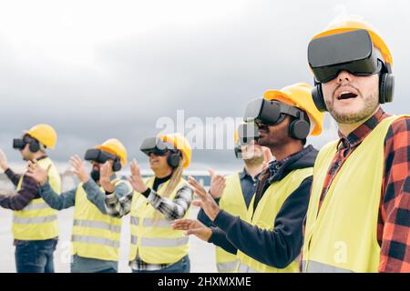 Multiracial team of industrial workers using virtual reality headsets at shipping cargo port - Metaverse and freight logistic concept - Focus on right Stock Photo
