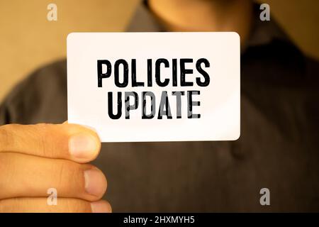 Businessman hand showing card with Policies Update message Stock Photo