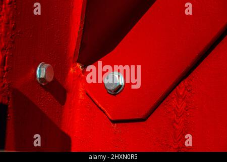 bolted connection of a massive steel structure painted in red, assembly of elements of a large steel structure of a support or bridge, selective focus Stock Photo