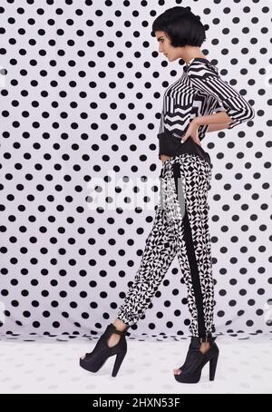 Polka dot style. Studio shot of a retro-stylish young woman against a black and white polka dot background. Stock Photo