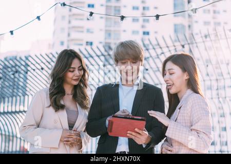 Asian business people working together and using a digital tablet. Group of professionals discussing outdoors Stock Photo