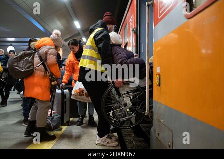 Kraków, Poland, 13/03/2022, A volunteer seen helping a woman in a wheelchair to board the train. Refugees from Ukraine wait for the trains to travel to western Europe. Credit: SOPA Images Limited/Alamy Live News Stock Photo
