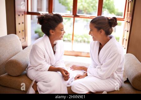 Chilling at the spa. Shot of two friends in bathrobes talking an laughing at a spa. Stock Photo