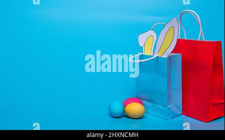 colored eggs and paper bag with ears on a blue background Stock Photo