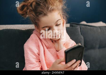 Close up portrait of a Caucasian girl child looking at cellphone screen checking children content in social networks. Stock Photo