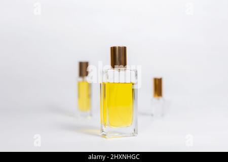 Three glass transparent rectangular bottles of golden perfume on white background. Minimal style perfumery template. Copy space Stock Photo