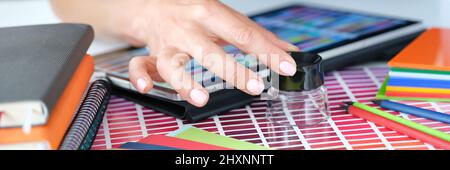 Woman designer looks through magnifying glass at color palette of red shades Stock Photo