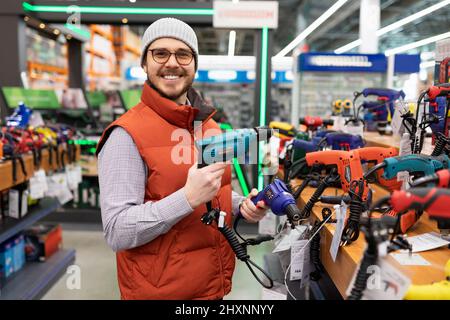 a satisfied customer purchases an electric drill and screwdriver in an electrical and construction equipment store Stock Photo