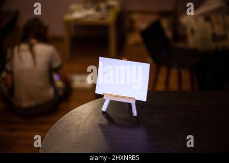 White sign for inscription. Small blank poster mounted on wood molar. Workpiece for inserting text or character. Object in room. Stock Photo