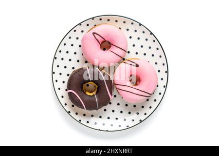 Classic chocolate, strawberry donut on white round plate with black peas isolated on white background Flat lat lay Top View Knolling Unhealthy and tas Stock Photo