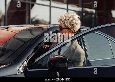 Elegant Woman Driver Getting in the Luxury Car Stock Photo