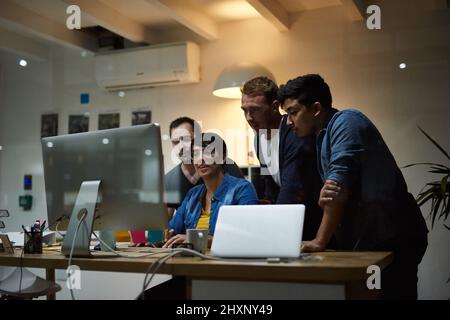 Discussing their ideas together. Shot of employees working in an office at night. Stock Photo