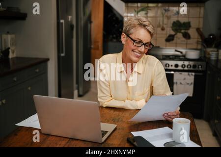 caucasian senior female happily reading insurance document with glasses Stock Photo