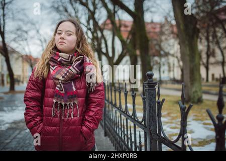 Young woman student with Down syndrome walking in street in winter Stock Photo