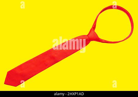 Tied red necktie isolated on yellow background. Stock Photo