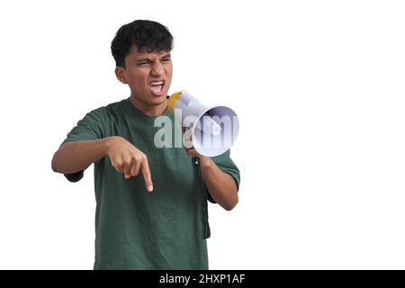Young peruvian man shouting through megaphone and pointing down, isolated. Stock Photo