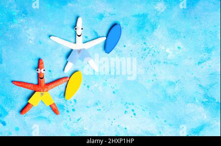 Funny starfish characters with surfboards lying on a blue background imitating water. Surfing vacation concept. Stock Photo