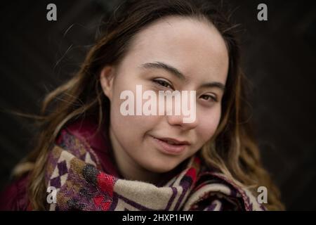Close-up of young woman with Down syndrome looking at camera on black background Stock Photo