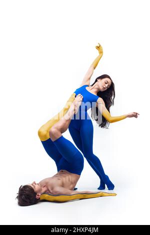 Contemporary art ballet, dance. Flexible young man and woman painted in blue and yellow colors of Ukrainian flag. Concept of feelings, emotions Stock Photo