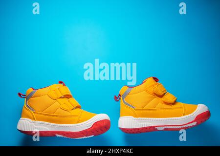 Yellow baby shoes. Kids sport sneakers isolated on blue background