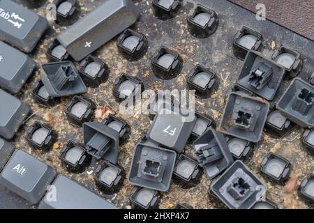Close-up of a very dirty disassembled computer keyboard on the table. Disassembling a computer keyboard with your own hands, cleaning the keyboard Stock Photo