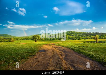 Rainbow over fields and trees on a farm on the edge of Lake Stock Photo