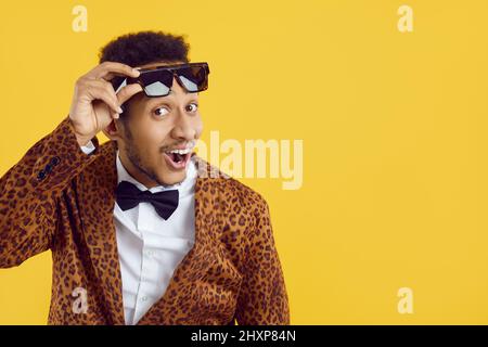 Happy black man in funky suit and sunglasses smiling and looking at camera on copy space background Stock Photo