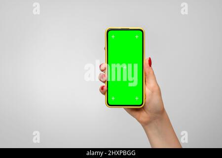 Smartphone in a yellow case with a green screen in a woman's hand Stock Photo