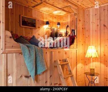alcove day bed in wood paneled room of Austrian country house with lamps, cushions, blanket and painting Stock Photo