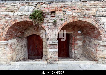Arched entrance with thick medieval walls to a building in the Bagno Vignoni. Tuscany, Italy Stock Photo