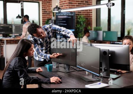 Cyber security agency coworker indicating on screen high usage of processing power on data grid information. Tech engineers detecting cloud leak and solve it with improved application coding. Stock Photo