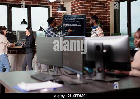 Cyber security company developers encrypting cloud processing data system using blockchain technology. Cybernetics engineers reviewing lines of code in order to secure mainframe database storage. Stock Photo