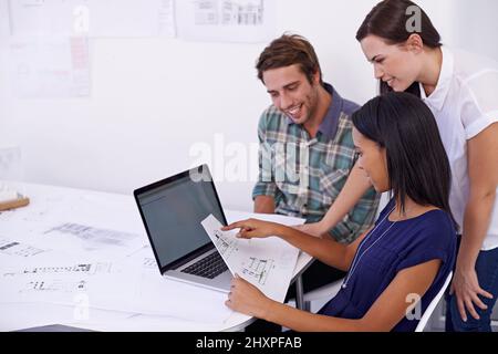 Three heads are better than one. Shot of a group of young architects working together in the office. Stock Photo
