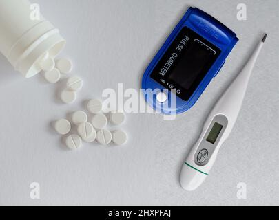 Digital pulse oximeter , thermometer and white pills on white background. Overhead view with copy space Stock Photo