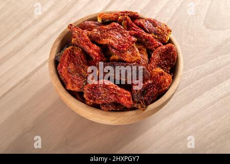 Bowl of dried tomatoes on wooden background, top view Stock Photo