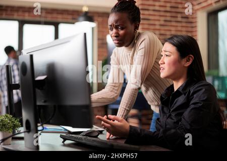 Mixed tech engineering team unsure about developed program result. Confused programmers questioning next move of artificial intelligence on database grid by using machine learning to defend system. Stock Photo