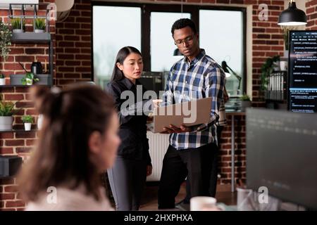 Cyber security agency employees using laptop to monitoring internet bandwidth and database used storage. Software developers analyzing received encrypted files by scanning them for malware. Stock Photo