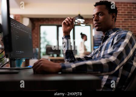 Pensive network engineer reflecting at failed data processing operation and security system unknown breach. Thoughtful software developer thinking of ways to upgrade encryption program. Stock Photo