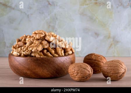 Bowl of walnuts and whole walnut kernels on color background Stock Photo