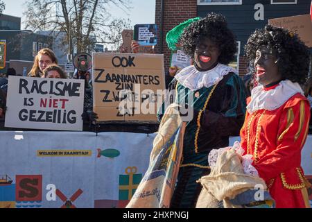 Several people disguised as Zwarte Piet pass in front of the demonstration of the anti-racist group in Zaandam Stock Photo