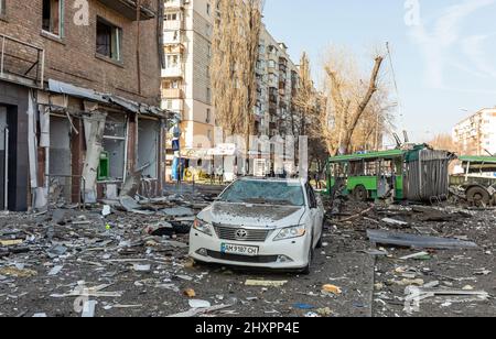 KYIV, UKRAINE - Mar. 14, 2022: EDS NOTE: GRAPHIC CONTENT, KYIV, UKRAINE - Mar. 14, 2022: War of Russia against Ukraine. The killed civilian lies on the sidewalk in front of the civilian house damaged by rocket attack the city of Kyiv  Stock Photo