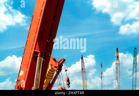 Crawler crane against blue sky and white clouds. Real estate industry. Crawler crane use reel lift up equipment in construction site. Crane for rent. Stock Photo