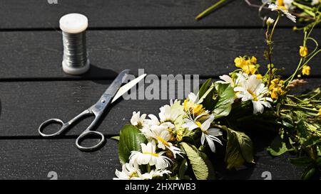 Making a beautiful flower crown, or flower wreath, using wire, scissor and wild flowers. Photo taken on Midsummer Eve, a holiday in Sweden. Stock Photo